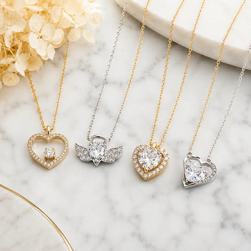Elegant gold and silver heart pendant necklaces with crystal zircon details displayed on white marble surface